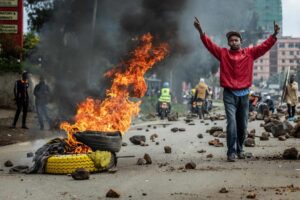 Protesters blocking a major road in Kenya with burning tires and matatus as police confront crowds during nationwide fuel price demonstrations